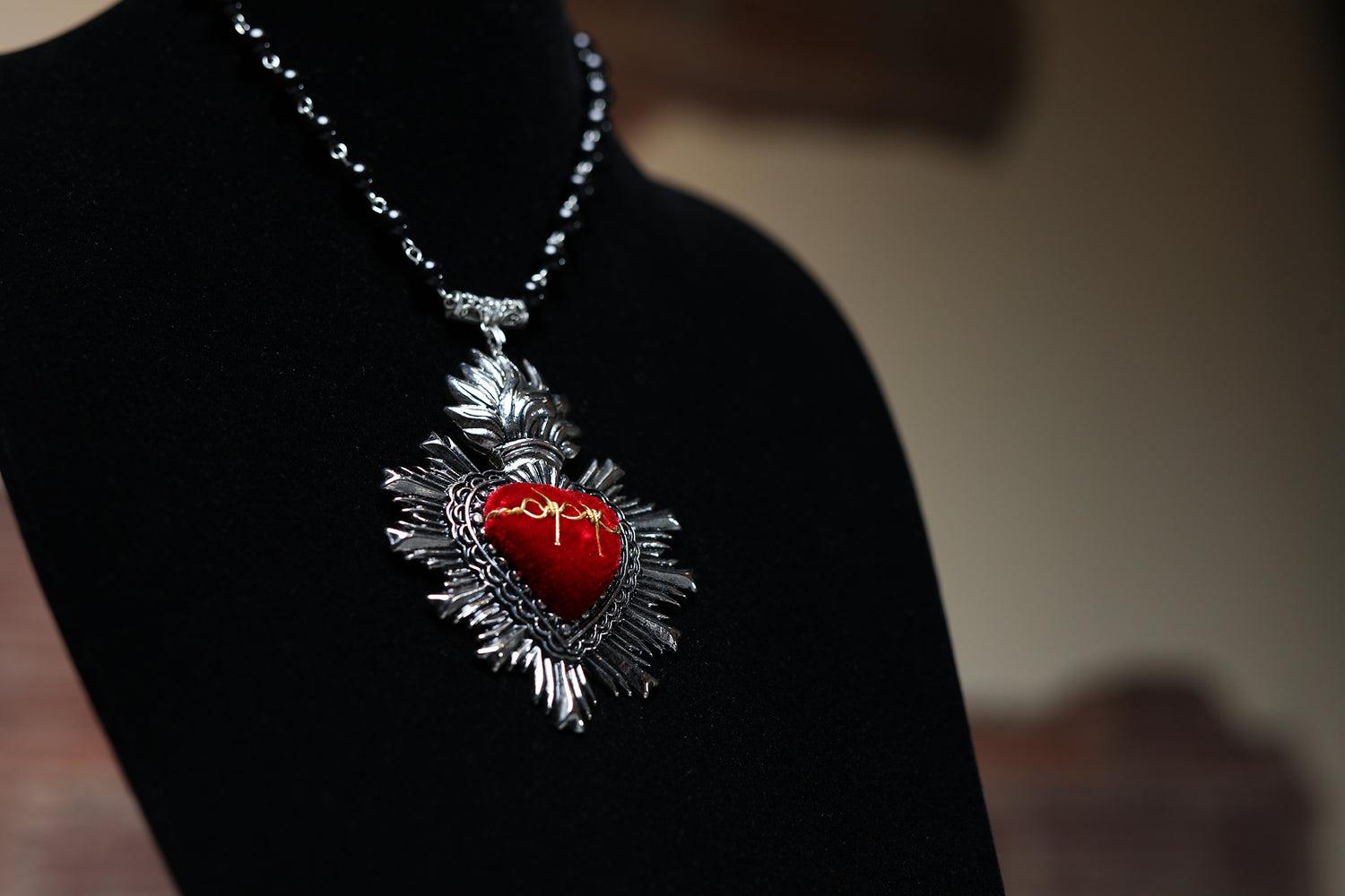 Red and silver cultural fashion necklace. the center is red and has a golden ornament, the chain is made with black and silver stones