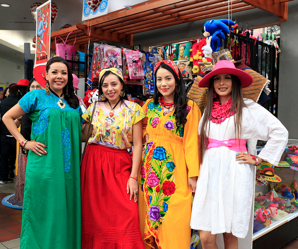 Models are wearing multicultural handmade products with Mexican representation. The floral embroidered dresses with painted images, handmade hats, and unique accessories