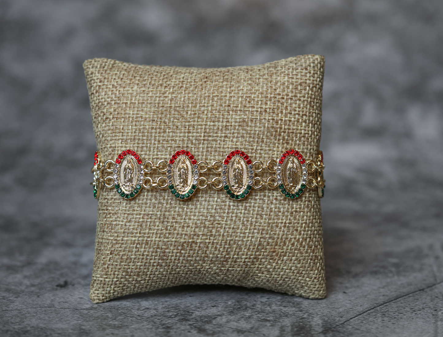 Multicultural oval-shaped gold-plated bracelets of the Virgin of Guadalupe with green and red stones.