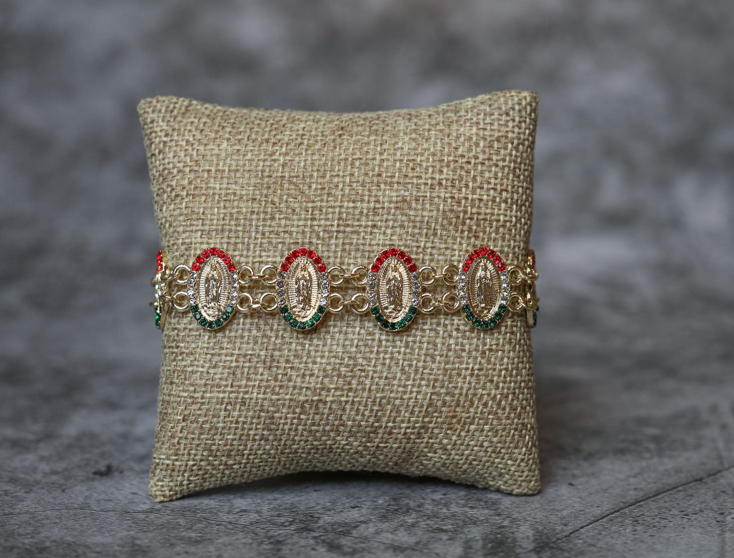 Multicultural oval-shaped gold-plated bracelets of the Virgin of Guadalupe with green and red stones.