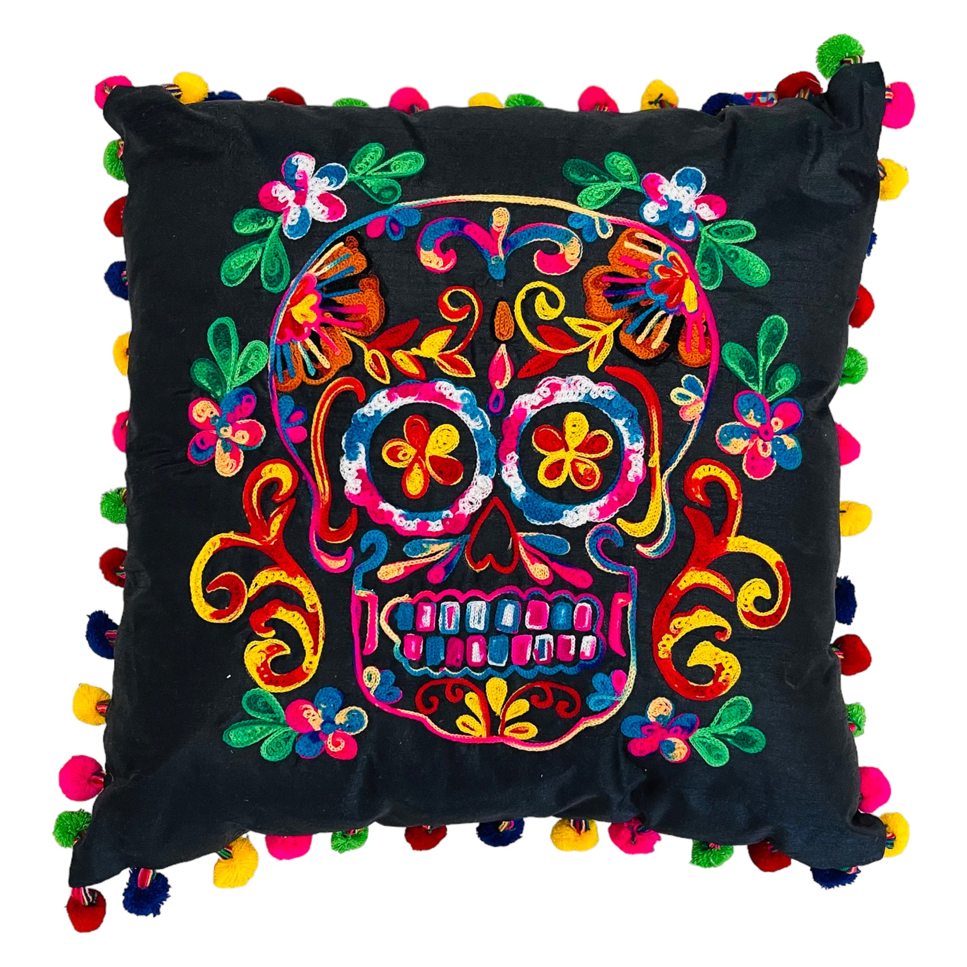 Hand embroidered black pillow with a skull in the center in pink, orange, blue and white with leaves around it. The border of the cushion is made with pompoms of different colors.