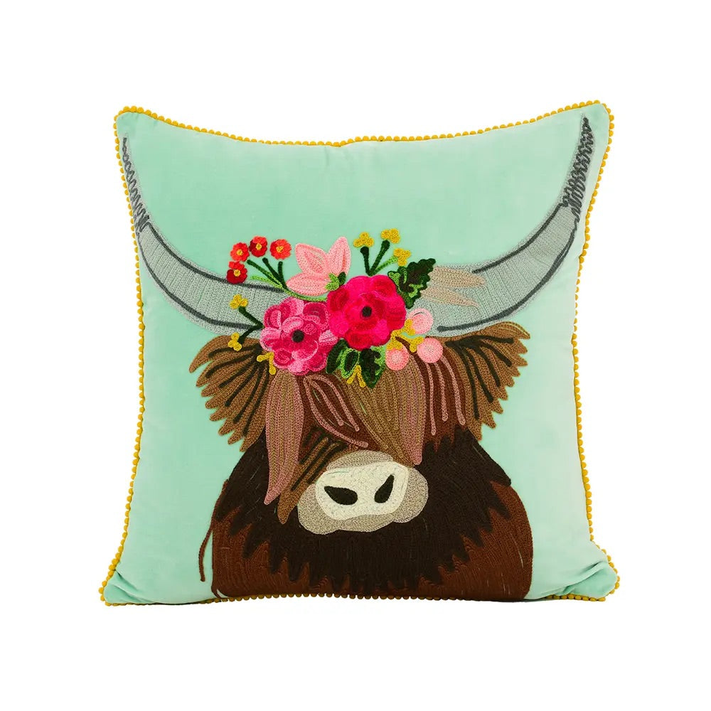 Hand embroidered teal pillow with Longhorn illustration in the center. It has on its head a wreath of flowers in different colors and with a yellow border.