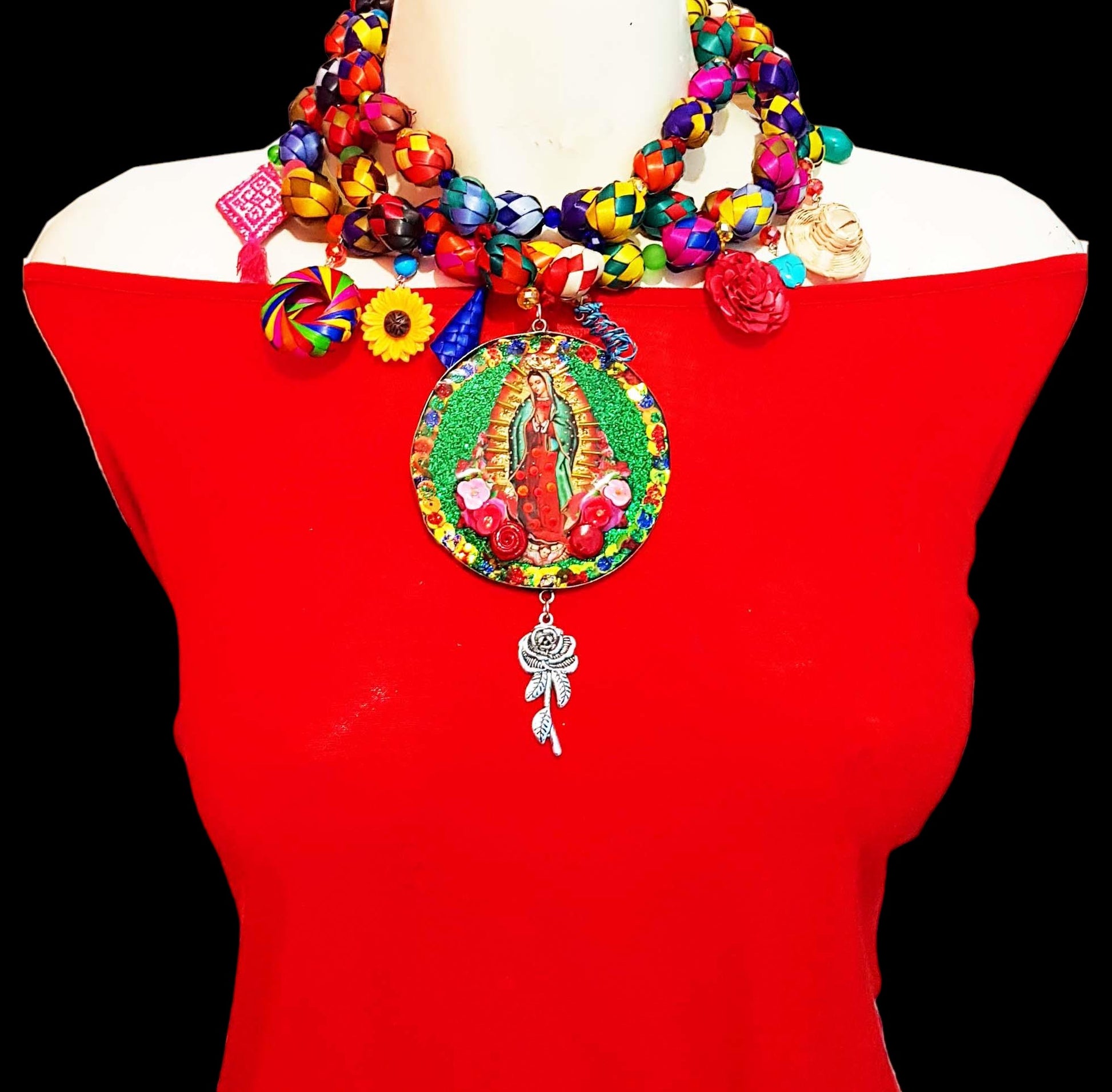 Medallones Choker necklaces with the Virgin of Guadalupe in the center with green background and red roses. The chain is designed by hand with paper mache of different colors with circular shape and hanging elements such as roses, hats.