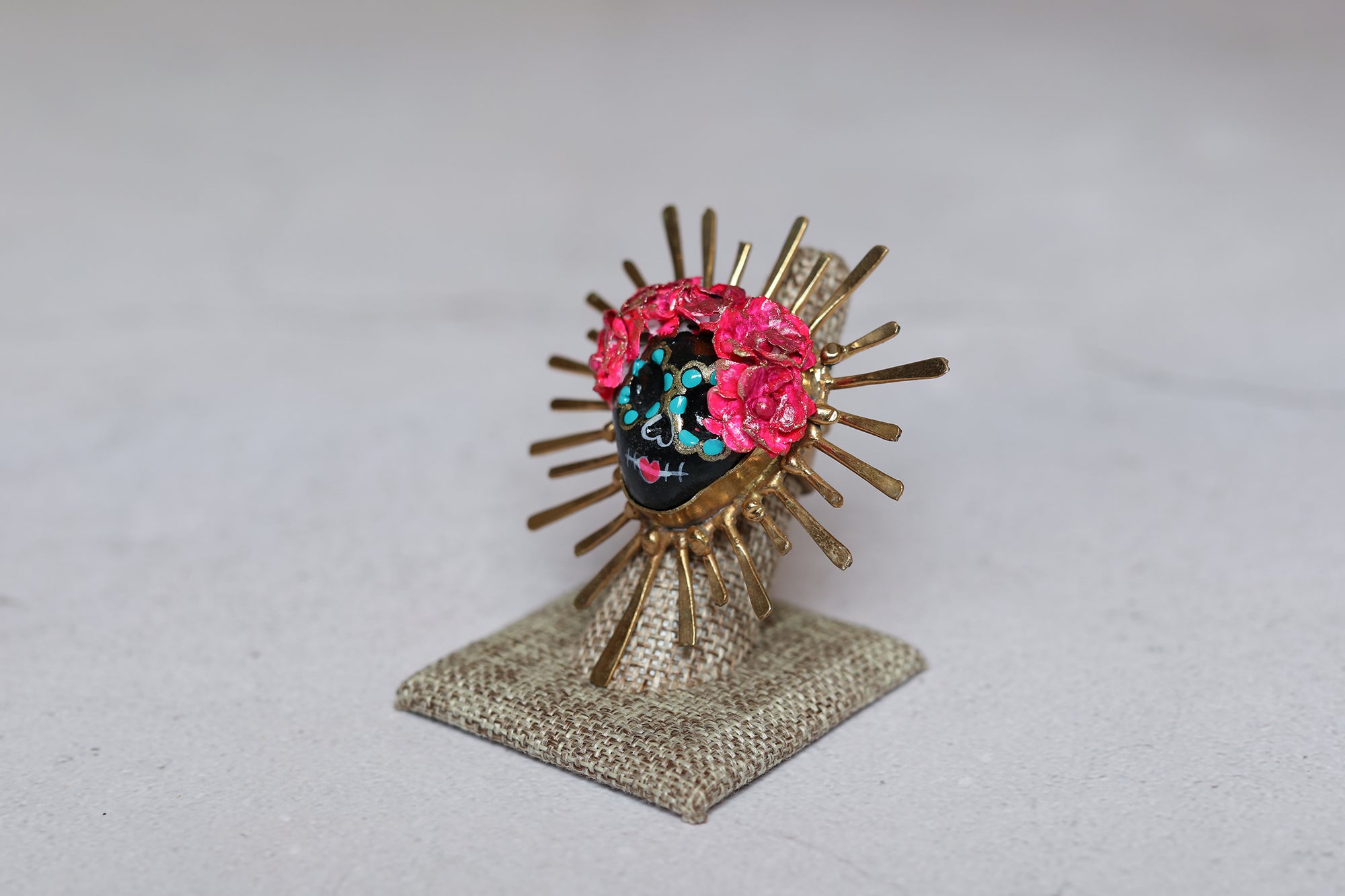 Black paper mache catrina ring with handmade pink roses and gold ornaments around it