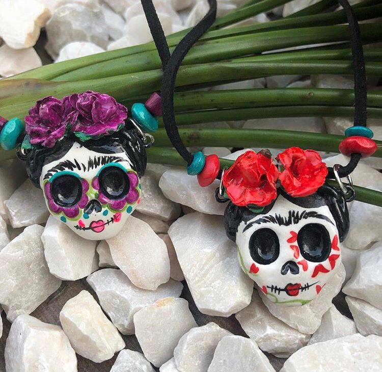 Two purple and red handmade paper mache catrinas necklaces inspired by the traditional Mexican Day of the Dead celebrations.