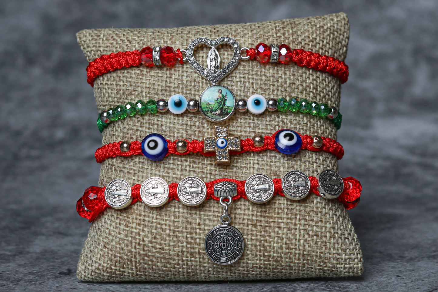 Four-charm bracelet package with different design. The first bracelet features a beautiful virgin mary charm, the second bracelet boasts a san benito charm, the third bracelet features a san juditas charm, and the fourth bracelet showcases an evil eye charm