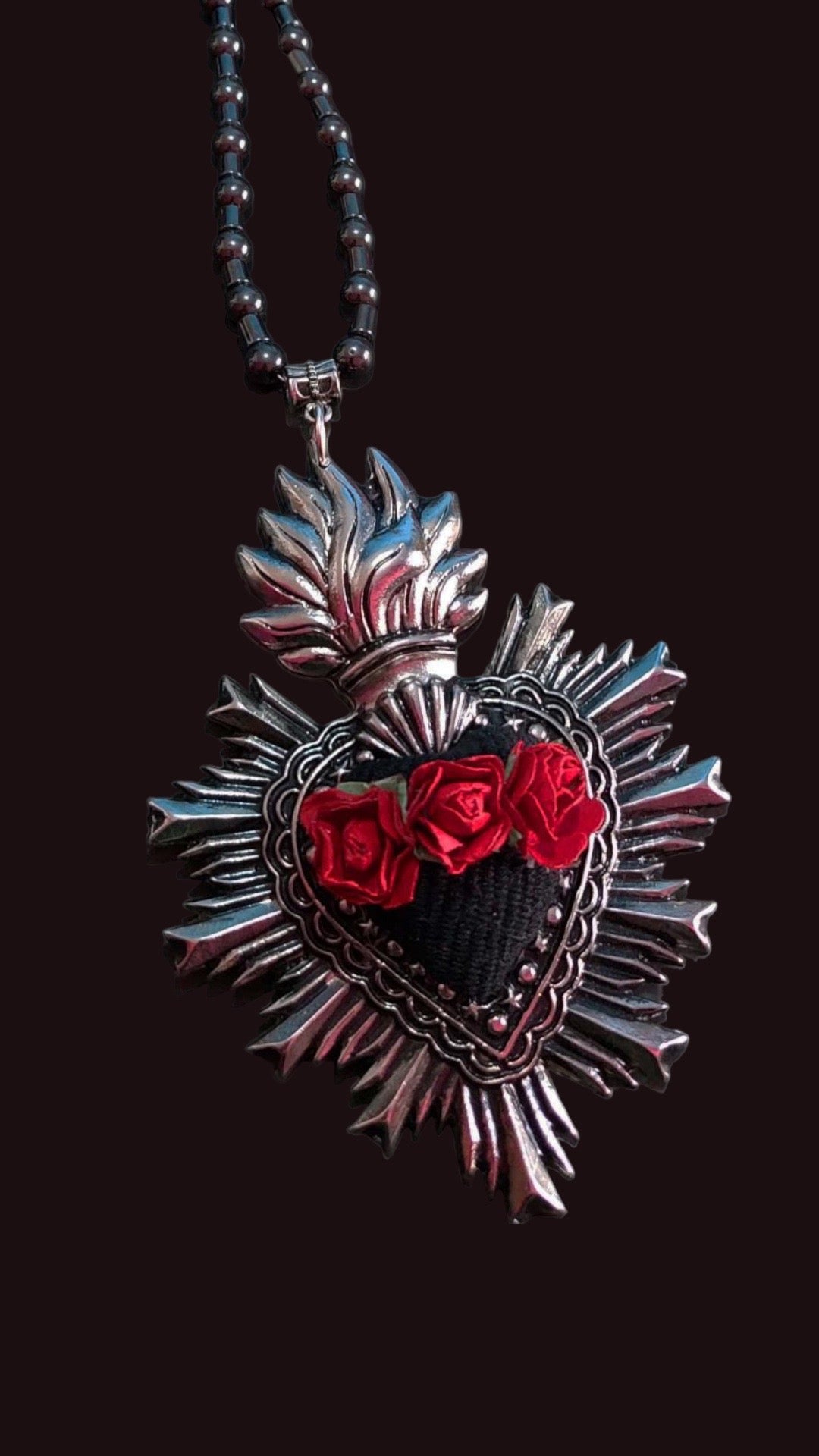 Black and red heart cultural fashion necklace. It has in the center three handmade red roses and around it has silver ornaments.