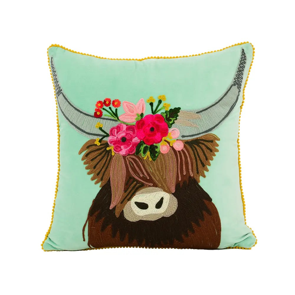 Hand embroidered teal pillow with Longhorn illustration in the center. It has on its head a wreath of flowers in different colors and with a yellow border. 