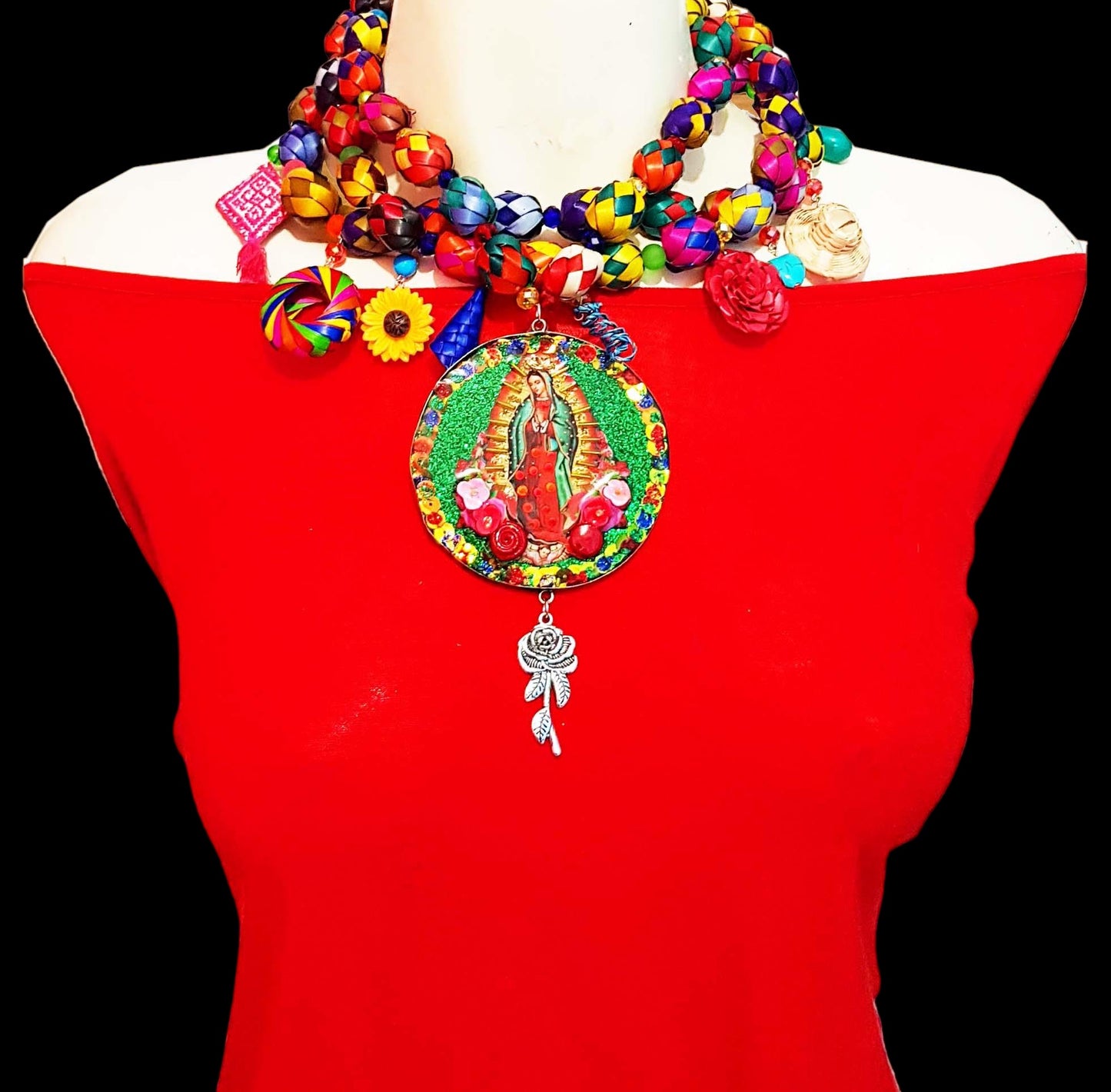 Medallones Choker necklaces with the Virgin of Guadalupe in the center with green background and red roses. The chain is designed by hand with paper mache of different colors with circular shape and hanging elements such as roses, hats. 