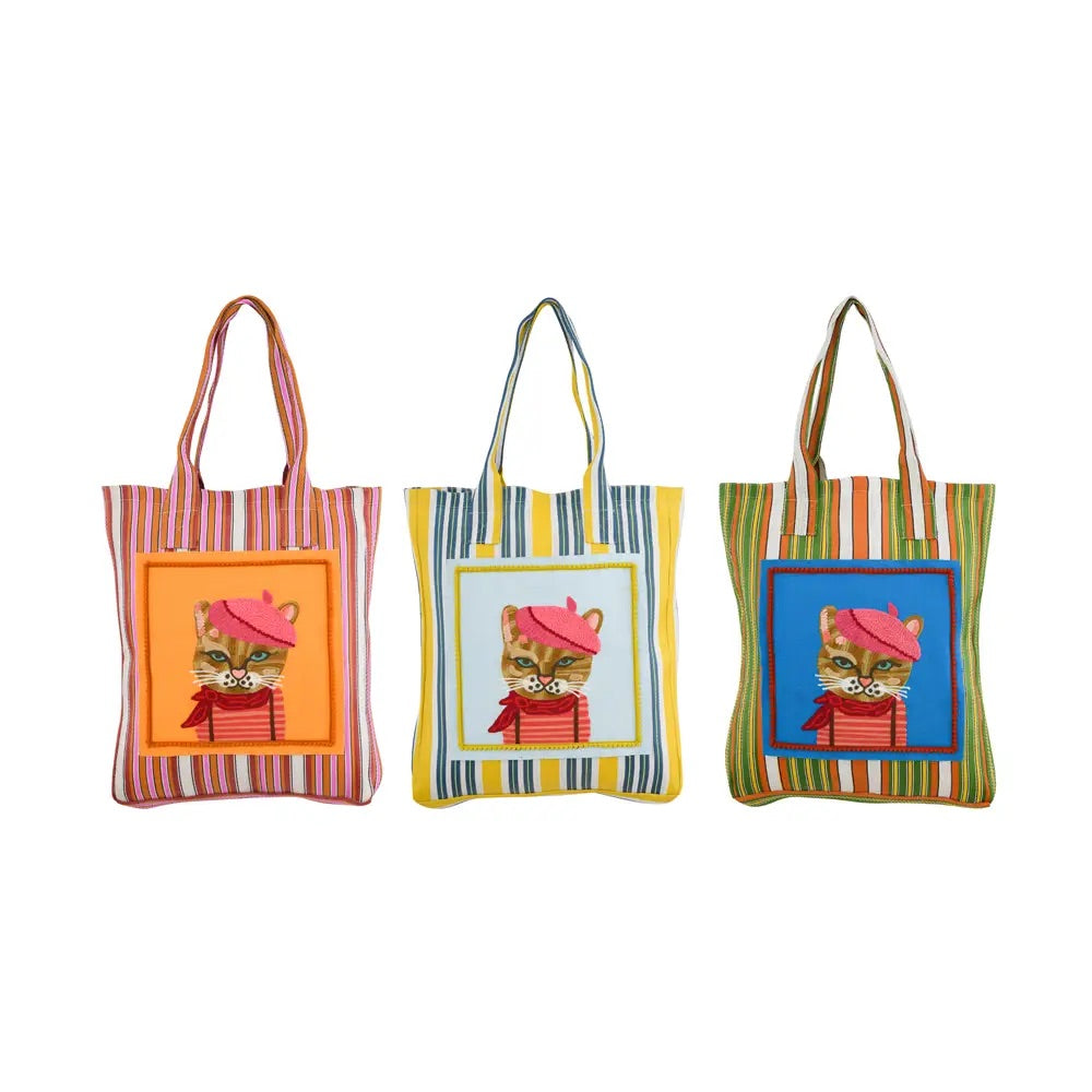 Recycled plastic tote bag multicolored and printed with the illustration of a brown cat in the middle. This one has different backgrounds and has a pink hat, a striped bag and a pink scarf with dots. 